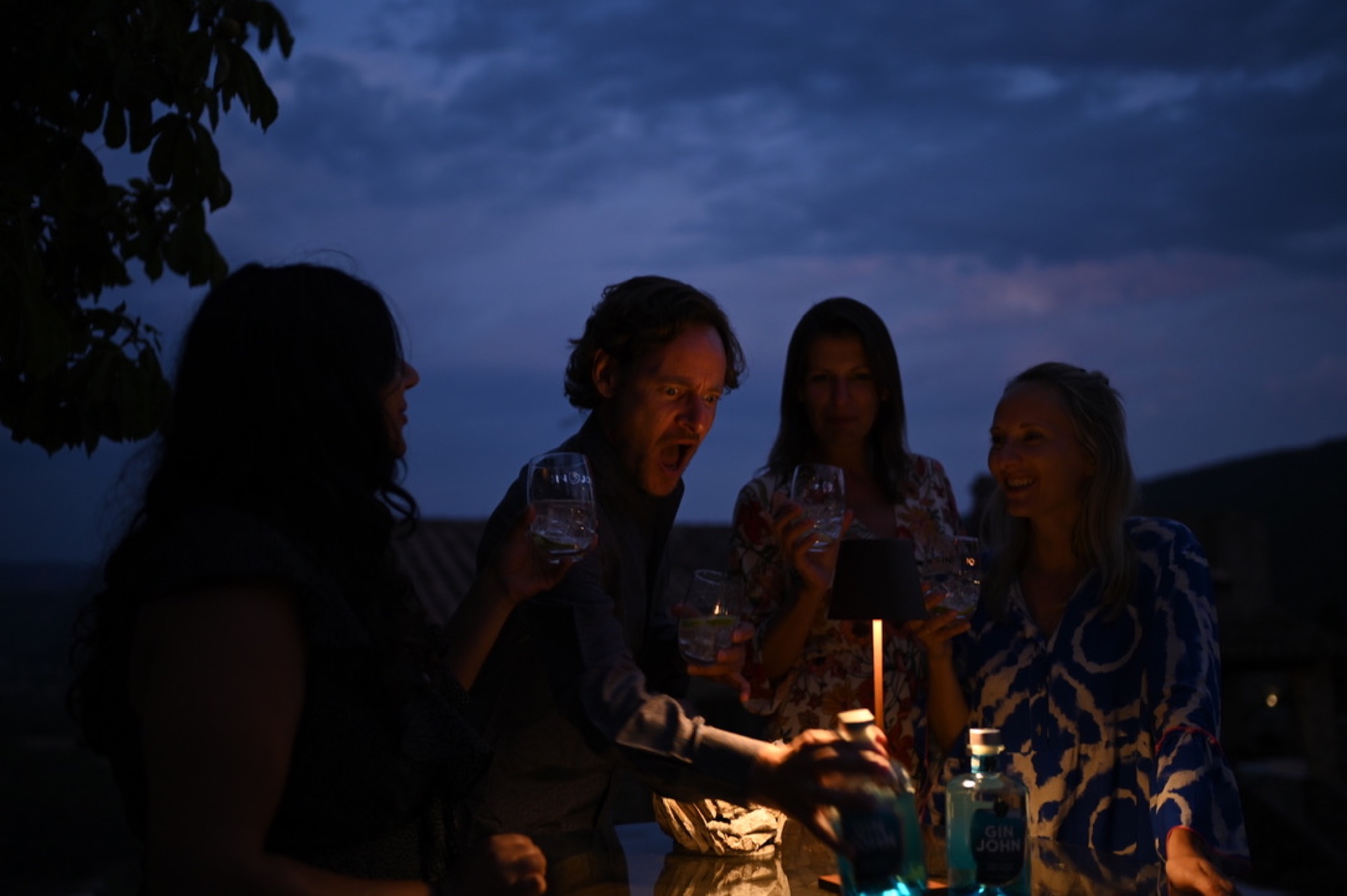 Vier Freunde mit Gin Tonics auf einer Toskana-Terrasse zur blauen Stunde